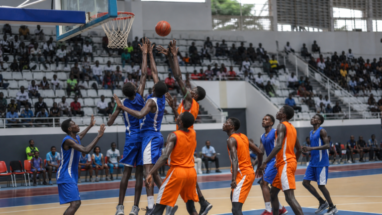 African youth basketball players contest a rebound in an indoor arena